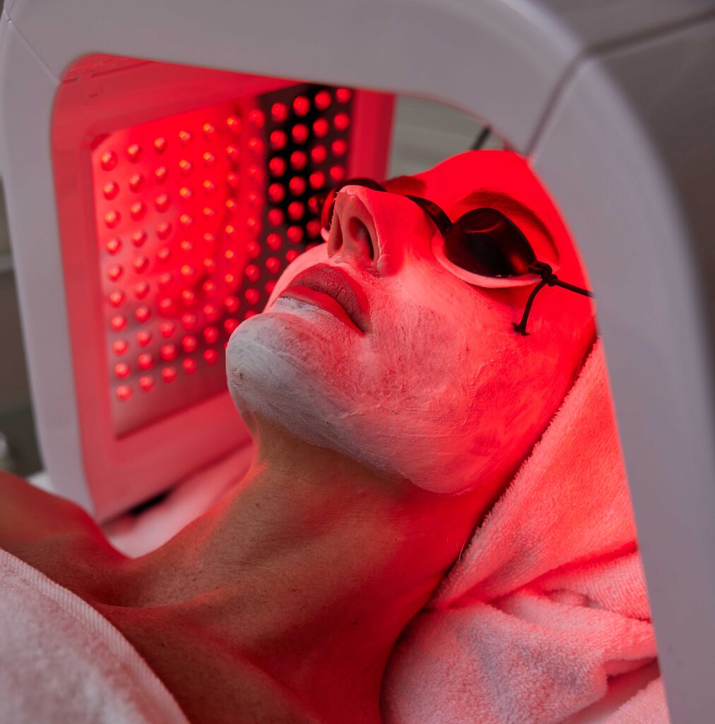 A person undergoing LED therapy, wearing protective glasses, with a facial mask for Skin Rejuvenations.