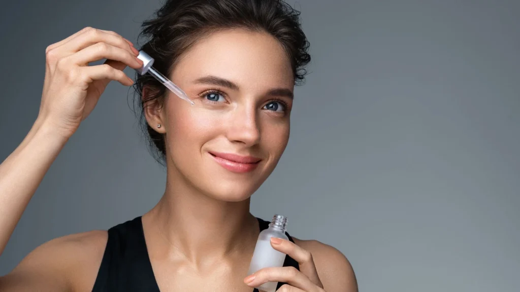 A woman applies a serum to her skin, highlighting her wellness-focused beauty routine.