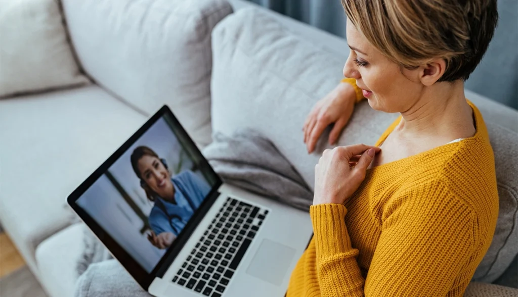 A woman participating in a telehealth consultation on her laptop, receiving personalized wellness advice.